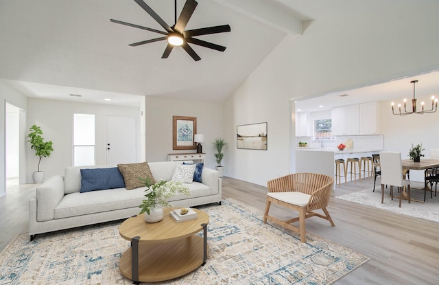 living room with ceiling fan with notable chandelier, beam ceiling, light wood-type flooring, and high vaulted ceiling