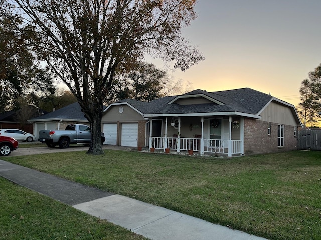 ranch-style house with a garage, covered porch, and a yard