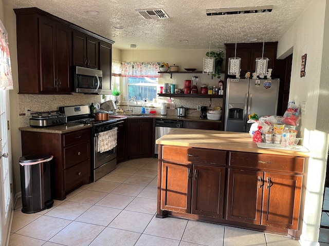 kitchen with wooden counters, appliances with stainless steel finishes, a textured ceiling, sink, and light tile patterned floors