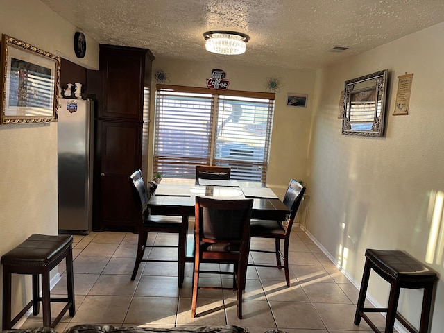 dining space with light tile patterned floors and a textured ceiling