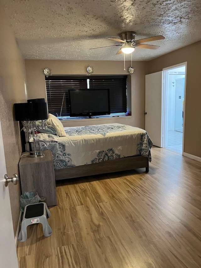 bedroom featuring ceiling fan, light hardwood / wood-style floors, and a textured ceiling