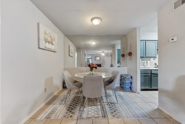 dining room featuring ceiling fan, light tile patterned floors, and a textured ceiling