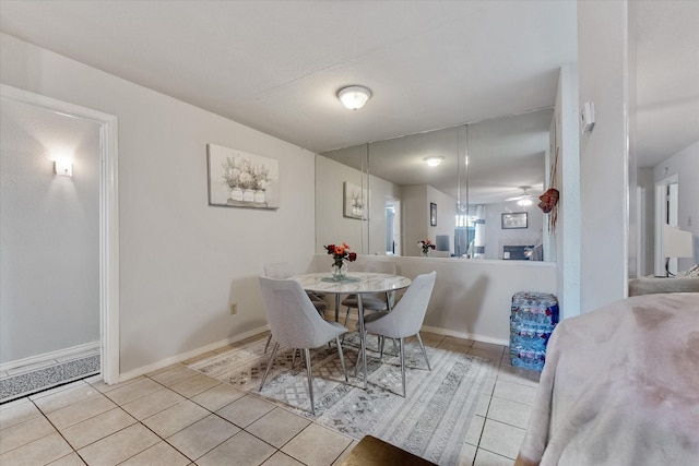 dining space featuring ceiling fan, light tile patterned flooring, and a textured ceiling