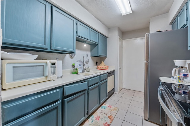 kitchen featuring blue cabinets, sink, light tile patterned floors, and stainless steel appliances