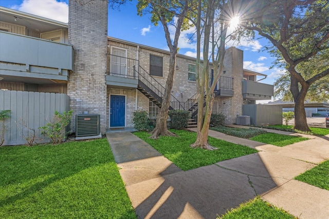 exterior space featuring central air condition unit and a front yard