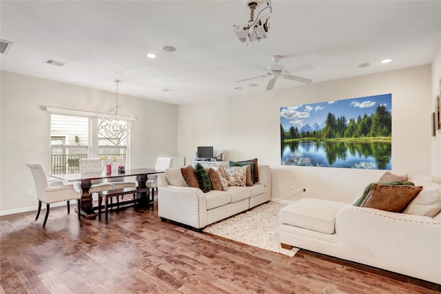 living room with hardwood / wood-style flooring and ceiling fan with notable chandelier