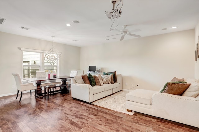 living room featuring wood-type flooring and ceiling fan with notable chandelier