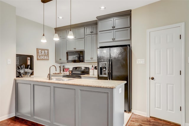 kitchen with pendant lighting, hardwood / wood-style flooring, kitchen peninsula, and black appliances