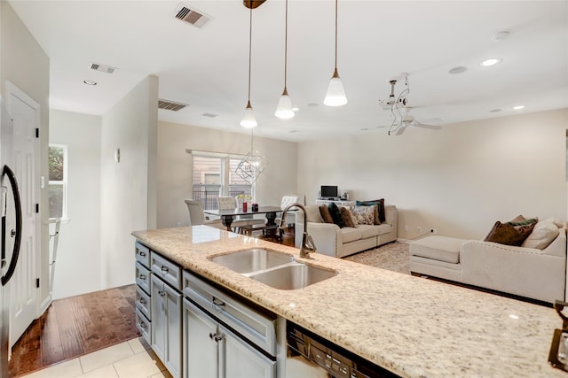 kitchen featuring sink, light tile patterned floors, ceiling fan with notable chandelier, light stone countertops, and decorative light fixtures