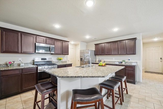 kitchen with a kitchen breakfast bar, a kitchen island with sink, sink, and stainless steel appliances