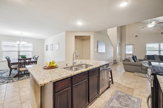 kitchen with dark brown cabinetry, sink, stainless steel appliances, pendant lighting, and a kitchen island with sink