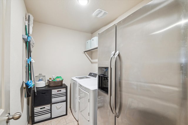 clothes washing area featuring light tile patterned floors and washer and dryer