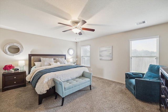 carpeted bedroom featuring ceiling fan and a textured ceiling