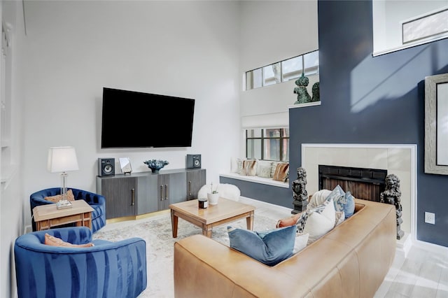 living room featuring a towering ceiling, a fireplace, and light hardwood / wood-style flooring