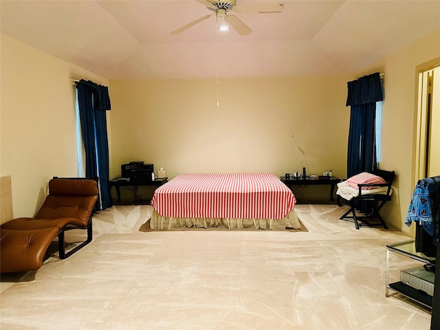 carpeted bedroom featuring a tray ceiling and ceiling fan