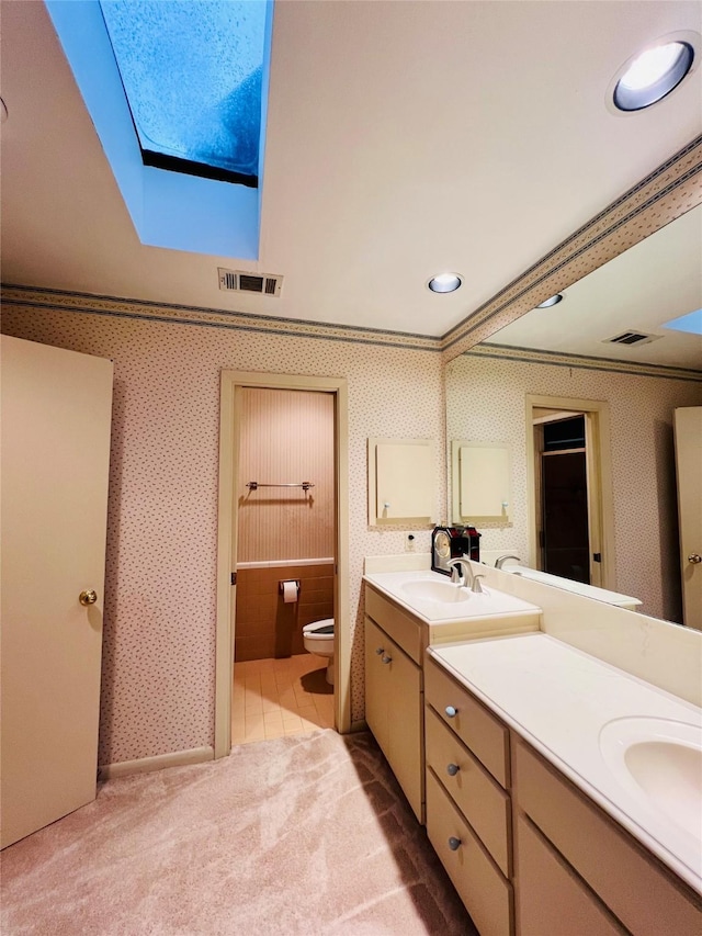 bathroom with vanity, a skylight, toilet, and crown molding