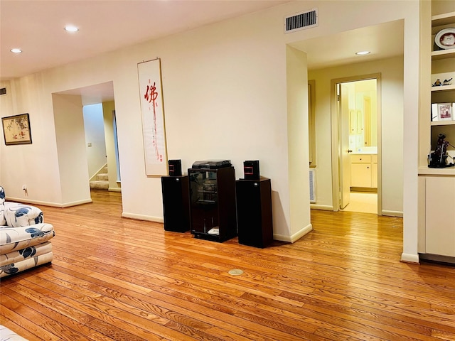 living room with built in shelves and light hardwood / wood-style floors