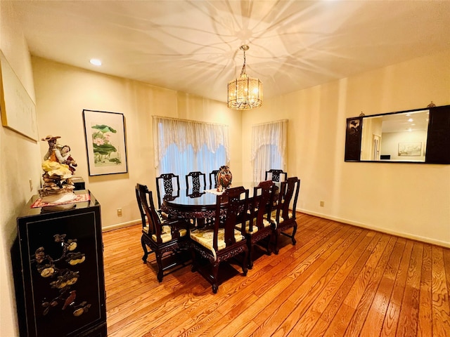 dining space featuring light wood-type flooring and a notable chandelier