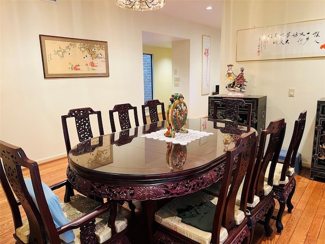 dining area with wood-type flooring and an inviting chandelier