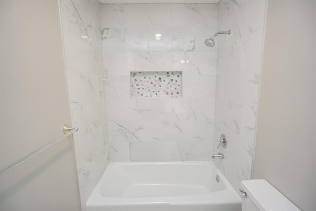 bathroom featuring toilet and tiled shower / bath