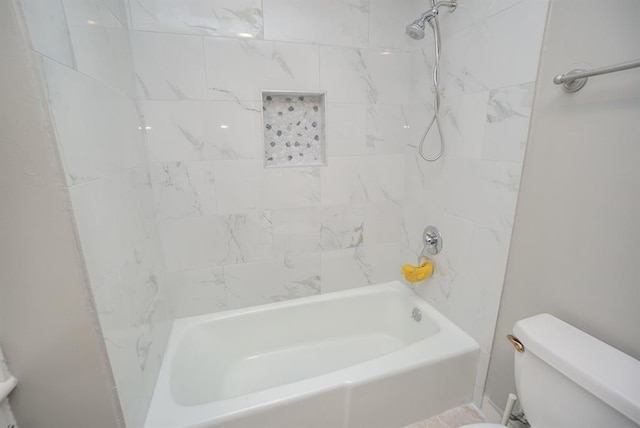 bathroom featuring tiled shower / bath combo and toilet