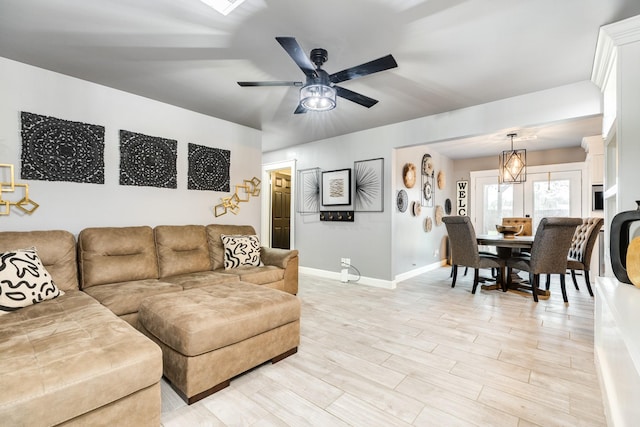 living room with ceiling fan with notable chandelier and light hardwood / wood-style floors