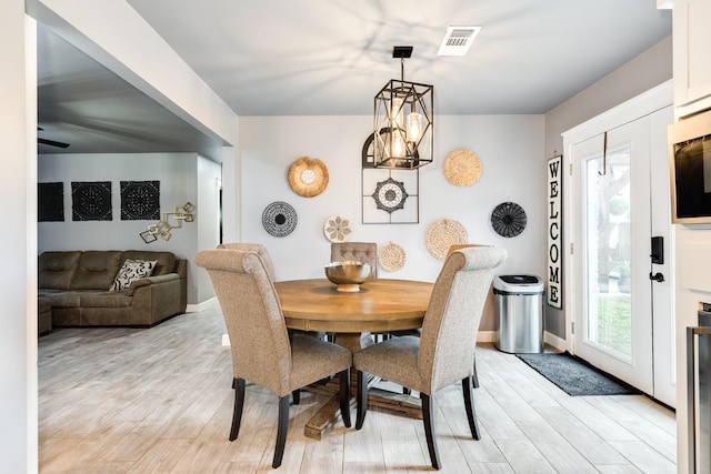 dining area with light wood-type flooring and a chandelier