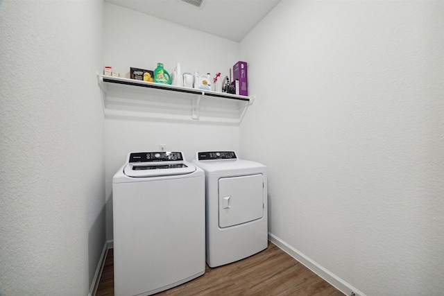 clothes washing area with hardwood / wood-style flooring and washing machine and dryer