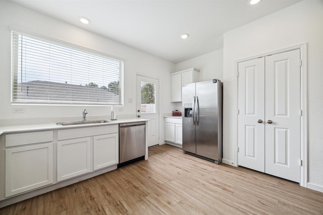 kitchen featuring sink, white cabinets, light wood-type flooring, and appliances with stainless steel finishes