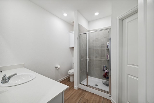 bathroom with hardwood / wood-style floors, vanity, toilet, and a shower with shower door