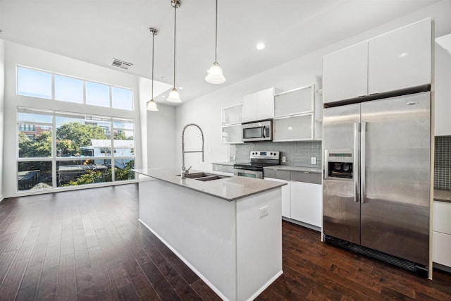 kitchen featuring pendant lighting, white cabinets, a center island with sink, sink, and stainless steel appliances