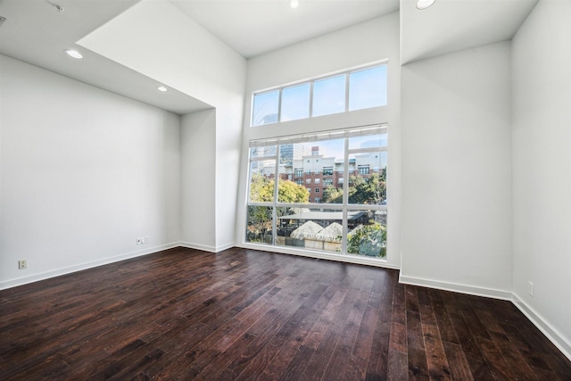 unfurnished room featuring a towering ceiling and dark hardwood / wood-style floors