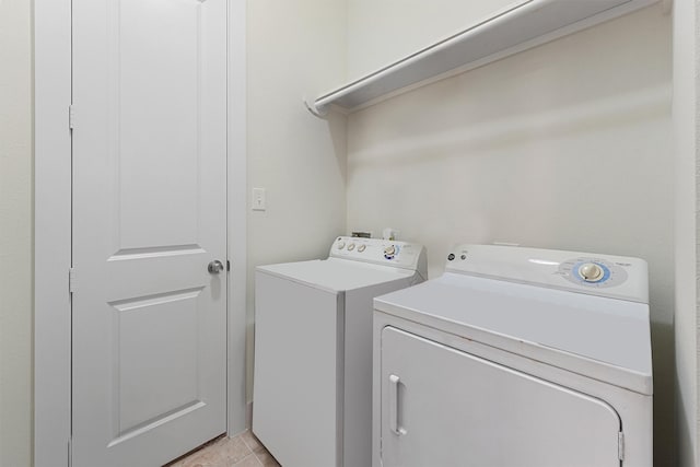 clothes washing area featuring washer and clothes dryer and light tile patterned flooring