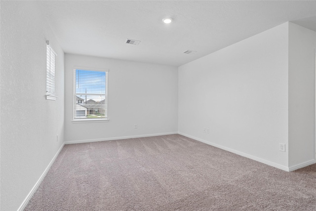 spare room featuring baseboards, carpet flooring, and visible vents