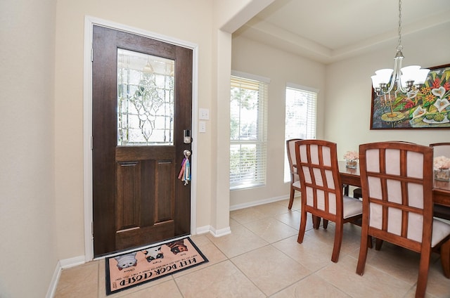 tiled entryway with a chandelier and a tray ceiling