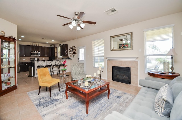 living room with light tile patterned flooring, ceiling fan, and a tiled fireplace