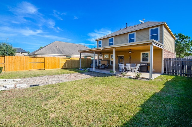 rear view of house with a patio, ceiling fan, and a lawn