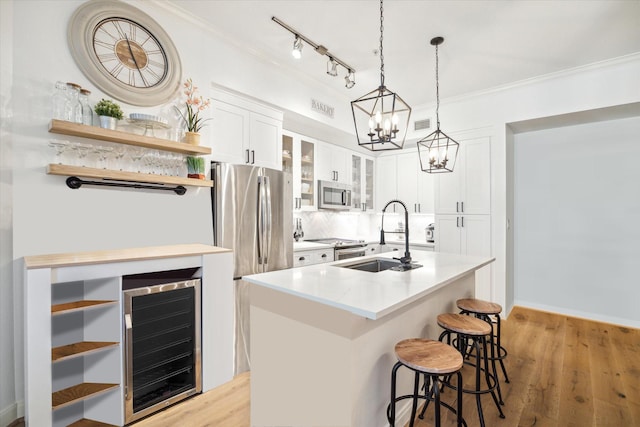 kitchen featuring stainless steel appliances, sink, white cabinets, wine cooler, and an island with sink