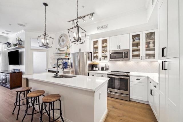 kitchen featuring sink, backsplash, a kitchen island with sink, white cabinets, and appliances with stainless steel finishes