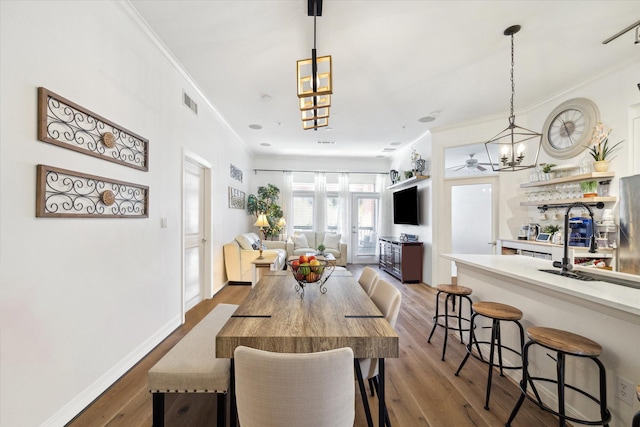 dining space featuring hardwood / wood-style floors, an inviting chandelier, and crown molding