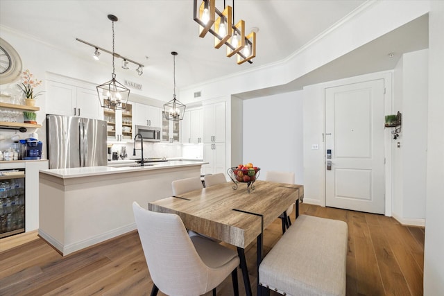 dining room with light hardwood / wood-style floors, beverage cooler, and crown molding