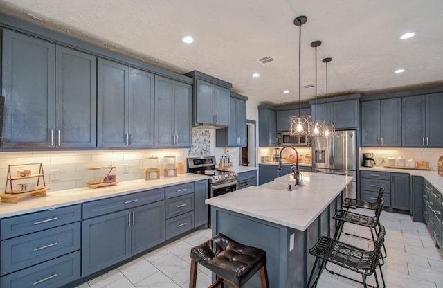 kitchen featuring a kitchen island with sink, hanging light fixtures, tasteful backsplash, a kitchen bar, and stainless steel appliances