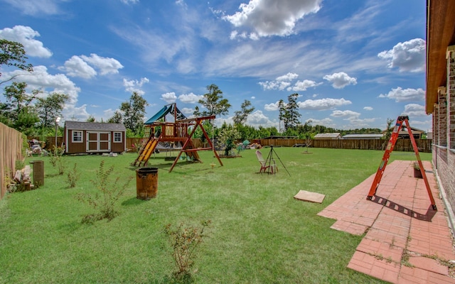 view of playground with a yard, a shed, and a patio area