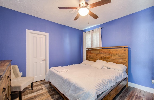 bedroom with ceiling fan, dark hardwood / wood-style flooring, and a textured ceiling