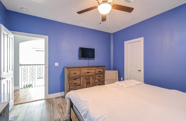 bedroom with ceiling fan, wood-type flooring, and a textured ceiling