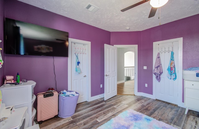 bedroom featuring ceiling fan, light wood-type flooring, and a textured ceiling