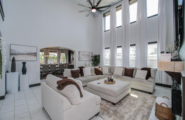 living room featuring a wealth of natural light, a towering ceiling, and ceiling fan with notable chandelier