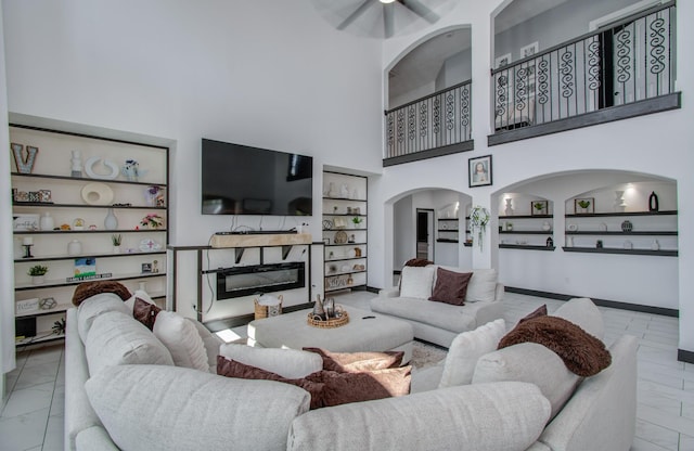 living room with ceiling fan, built in features, and a high ceiling