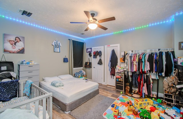 bedroom with ceiling fan, light hardwood / wood-style flooring, and a textured ceiling