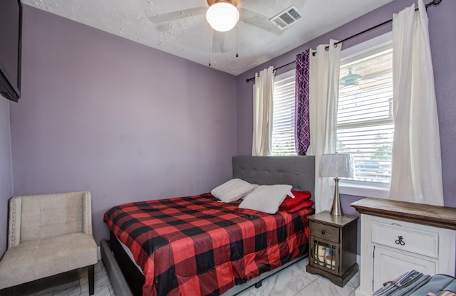 bedroom featuring multiple windows, a textured ceiling, and ceiling fan